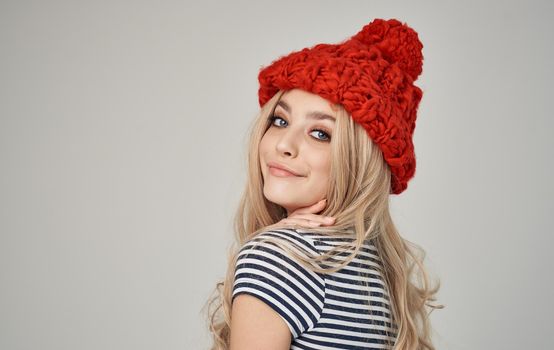 beautiful blonde in a warm hat and striped T-shirt on a light background. High quality photo