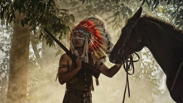 The Indians are riding a horse and spear ready to use In light of the Silhouette, American Indian warrior, chief of the tribe. man with feather he