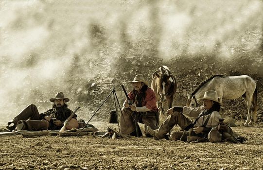 Rider as cowboy outfit costume with a horses and a gun held in the hand against smoke and sunset background