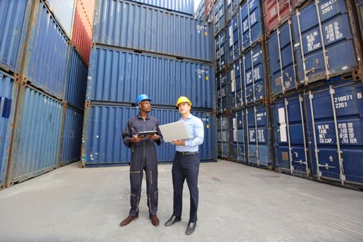 Engineer or supervisor checking and control loading Containers box from Cargo at harbor.Foreman control Industrial Container Cargo freight ship at industry.Transportation and logistic concept. 