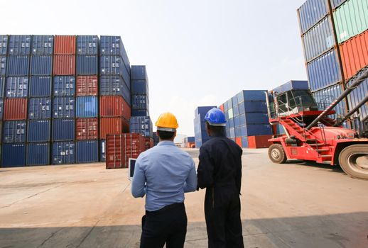 Engineer or supervisor checking and control loading Containers box from Cargo at harbor.Foreman control Industrial Container Cargo freight ship at industry.Transportation and logistic concept. 