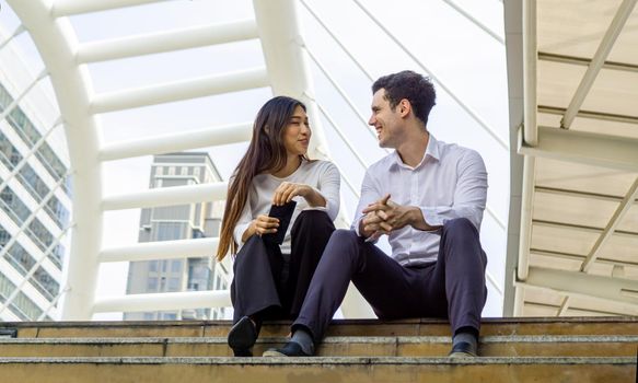 Two asian business people sitting on stair outside office, business concept