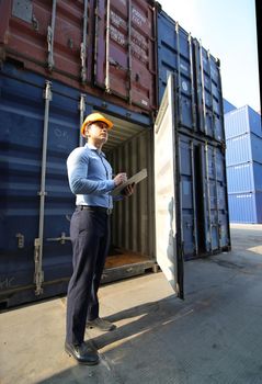 Engineer or supervisor checking and control loading Containers box from Cargo at harbor.Foreman control Industrial Container Cargo freight ship at industry.Transportation and logistic concept. 