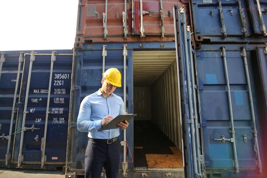 Engineer or supervisor checking and control loading Containers box from Cargo at harbor.Foreman control Industrial Container Cargo freight ship at industry.Transportation and logistic concept. 