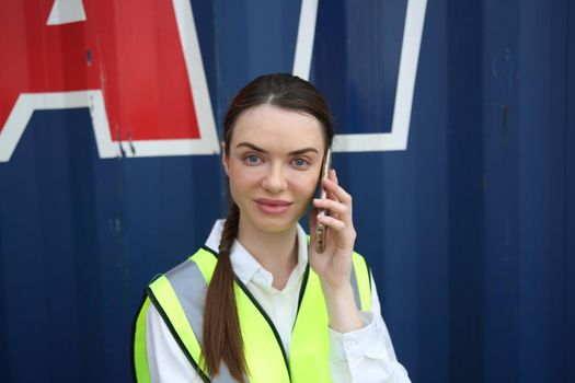 Smiling female worker talking on the phone at construction site.