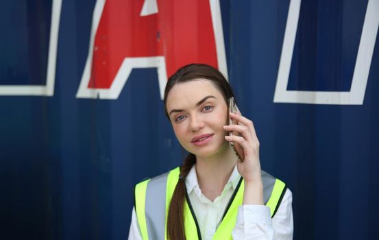 Smiling female worker talking on the phone at construction site.