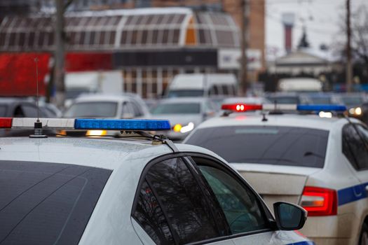 two police cars lights in city street at winter day with cars traffic in blurry background.