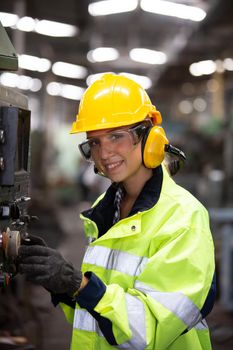 Woman worker wearing safety goggles control lathe machine to drill components. Metal lathe industrial manufacturing factory