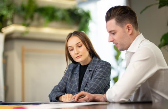 Close-up image of two attractive young people having a business meeting in a modern cafe.