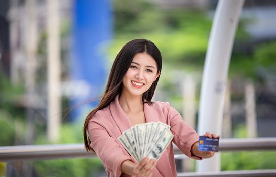 young asian women holding money and credit card at outdoor.