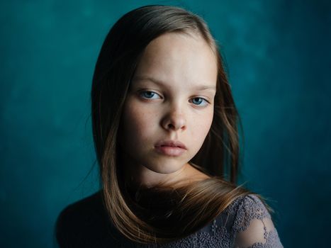 Portrait of a beautiful little girl in a gray dress on a turquoise background and blue eyes. High quality photo