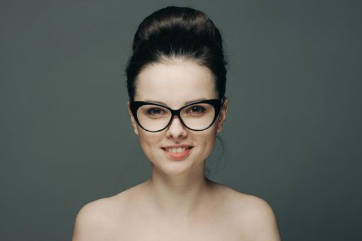 cute brunette with glasses naked shoulders gathered hair fashion. High quality photo