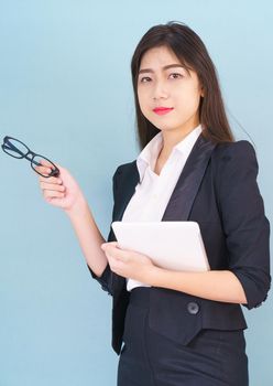 Young Asain women in suit standing using her digital tablet against blue background