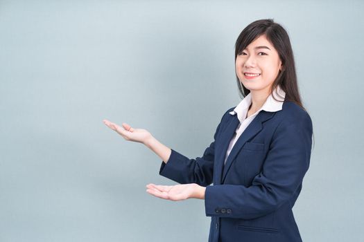 Asian woman in suit open hand palm gestures with empty space isolated on gray background