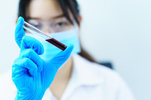 Technician scientist analyzing holding blood sample in test tube in laboratory for testing it on COVID, COVID-19, coronavirus virus analysis