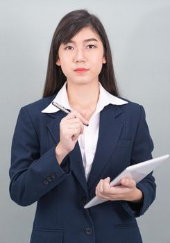 Woman in suit using computer digital tablet isolated on gray background