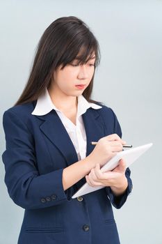 Asian woman in suit using computer digital tablet isolated on gray background