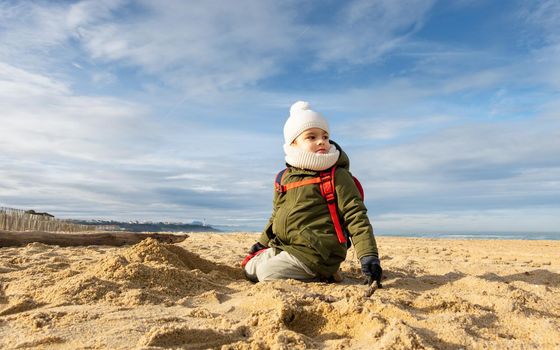 Little boy looking away on beach, beautiful winter season