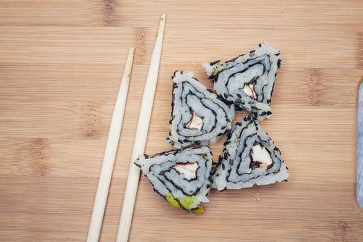sushi rolls chopsticks wooden board top view. High quality photo