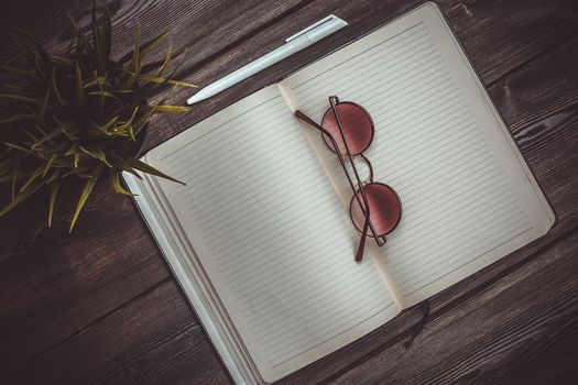 open notepad with pen and office glasses mobile phone flower in a pot top view interior. High quality photo