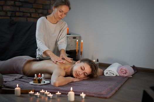 Relax and enjoy spa salon getting massage professional masseur Woman lying naked back relax on floor blanket Body care Hands treatment Acupressure trigger points Prevention back muscles pain