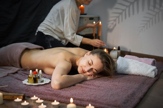 Relax and enjoy spa salon getting massage professional masseur Woman lying naked back relax on floor blanket Body care Hands treatment Acupressure trigger points Prevention back muscles pain