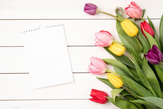 Top view of blank calendar with colorful tulips on white background. Mock up design