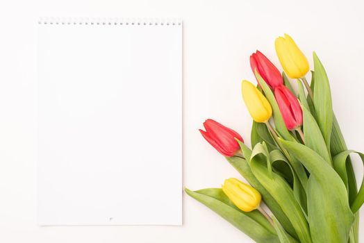 Top view of blank calendar with colorful tulips on white background. Mock up design