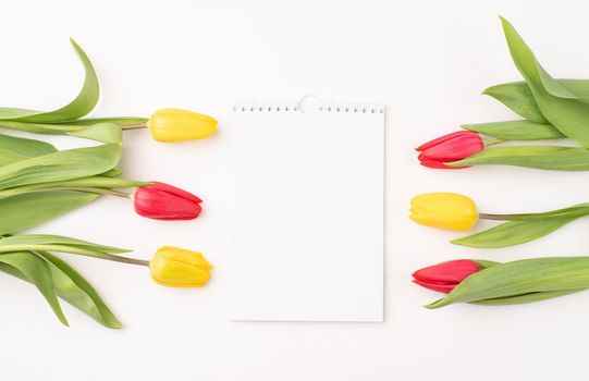 Top view of blank calendar with colorful tulips on white background. Mock up design