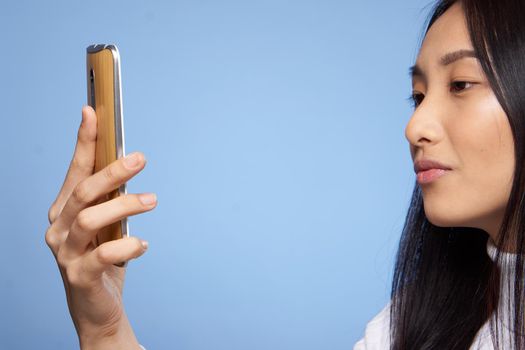 pretty brunette with phone in hands communication internet technology blue background studio. High quality photo