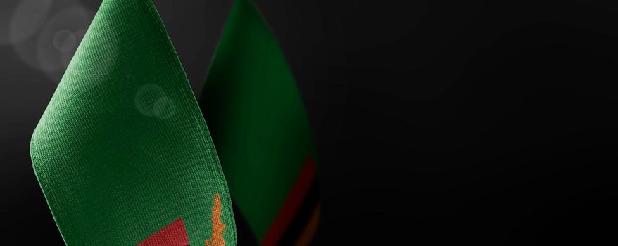 Small national flags of the Zambia on a dark background.