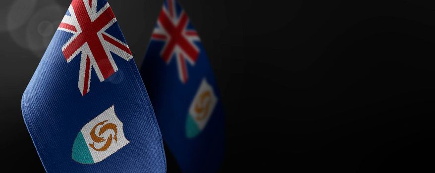 Small national flags of the Anguilla on a dark background.