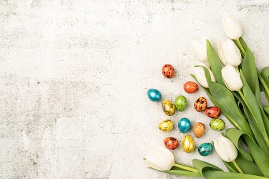 Easter and spring concept. Top view of white tulips and colored easter eggs on concrete backgrund with copy space