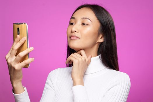 pretty asian woman white sweater phone in hand communication message. High quality photo