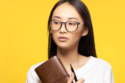 woman of asian appearance with notepad in hands and pen glasses elegant style work. High quality photo