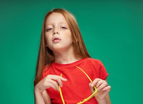 cute girl red hair gestures with hands emotions childhood school Green background. High quality photo