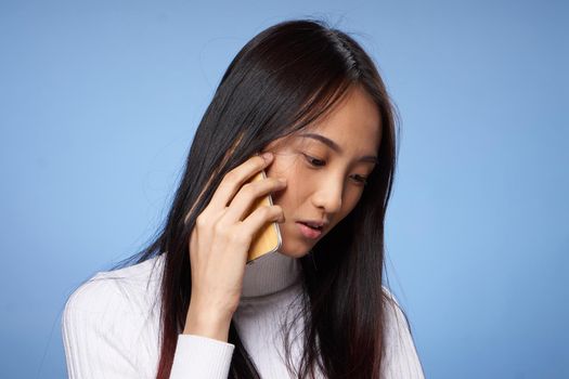 woman korean appearance talking on mobile phone on blue background. High quality photo