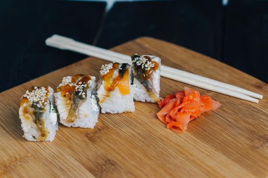 sushi rolls red ginger chopsticks wood board close-up. High quality photo