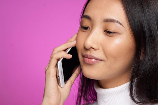 asian woman talking on the phone cropped view pink background. High quality photo