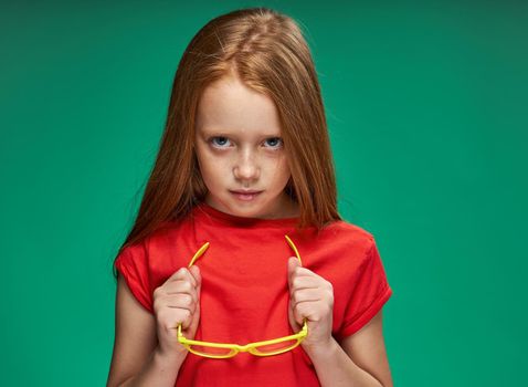 cute girl red hair gestures with hands emotions childhood school Green background. High quality photo