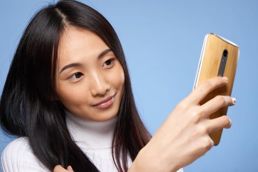 attractive woman asian appearance phone in hands technology lifestyle blue background. High quality photo