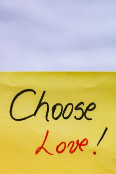 Choose love handwriting text close up isolated on yellow paper with copy space.