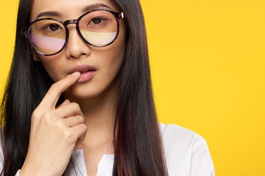 woman asian appearance elegant style glasses hand near face yellow background. High quality photo
