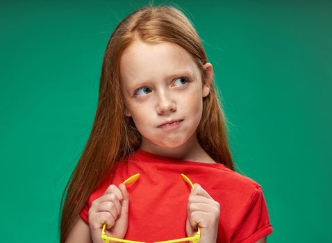 cute girl red hair gestures with hands emotions childhood school Green background. High quality photo