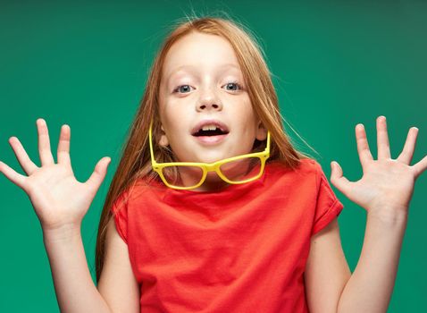 cute girl red hair gestures with hands emotions childhood school Green background. High quality photo