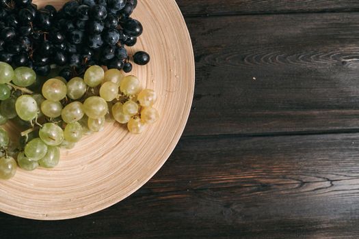 grapes on a plate wooden background fruit freshness. High quality photo