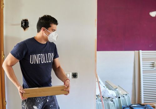 Worker moving boxes of tiles in a purple room with a blue t-shirt