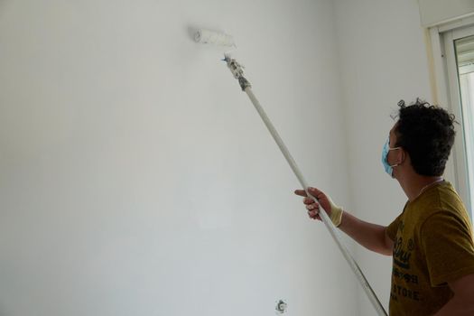 Painter painting a white room with a roller