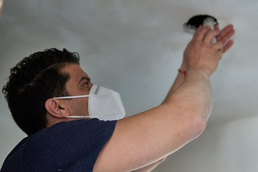 Worker changing a light bulb with a mask