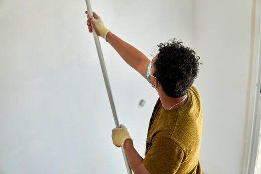 Painter painting a white room with a roller